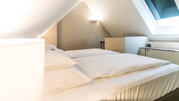 A bedroom with a bed, a desk, and a window.