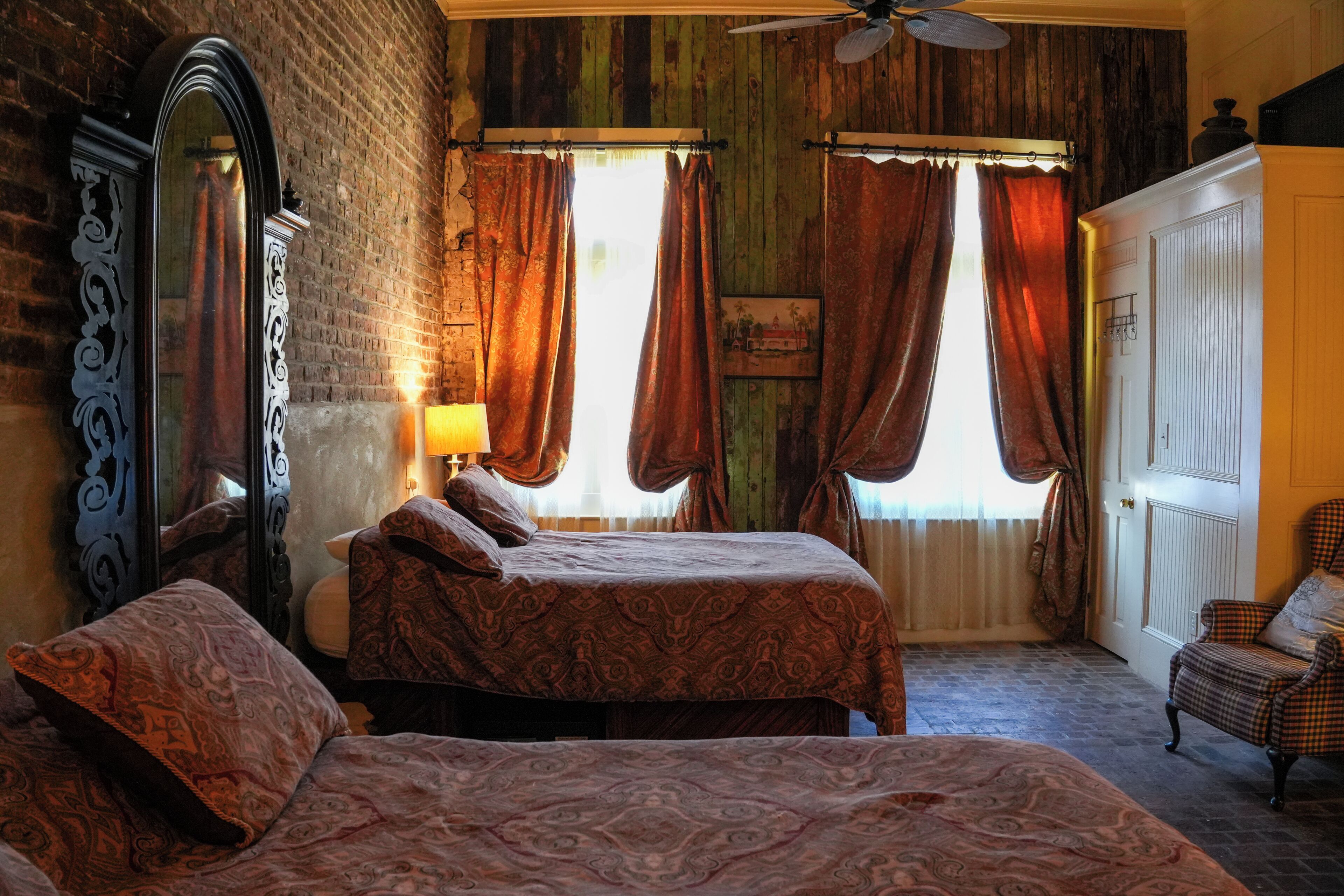 A bedroom with a bed, a chair, a mirror, and a door.