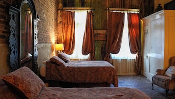 A bedroom with a bed, a chair, a mirror, and a door.