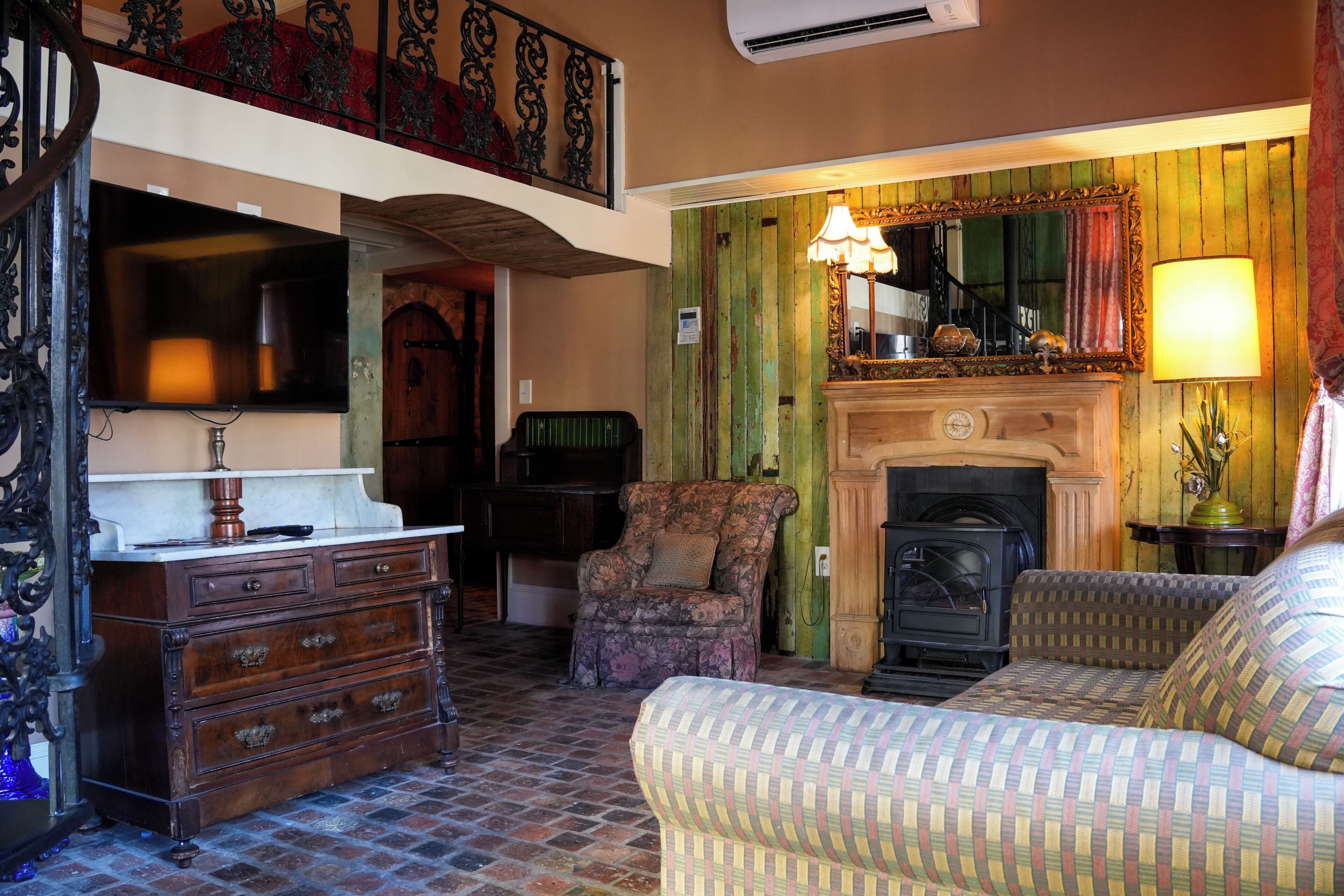 A traditional room with a fireplace, a sofa, a chair, and a dresser.