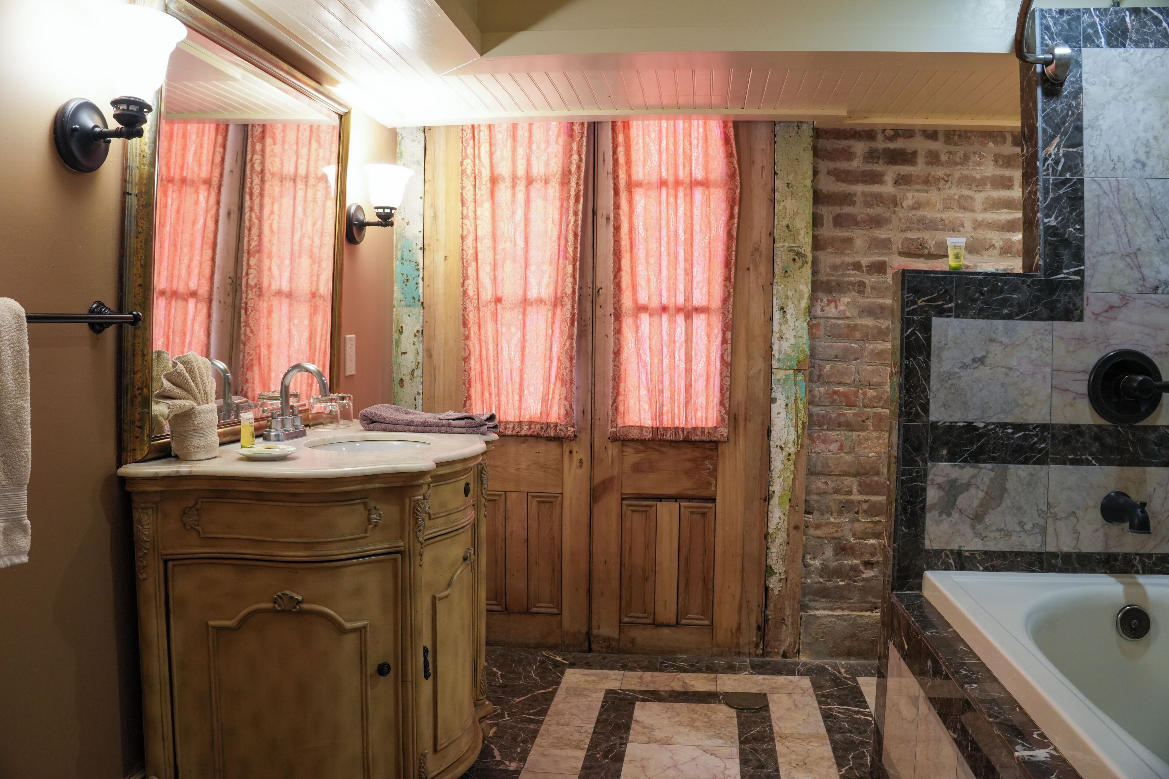 Un baño con tocador de madera, una bañera y un espejo grande.