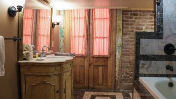 Un baño con tocador de madera, una bañera y un espejo grande.
