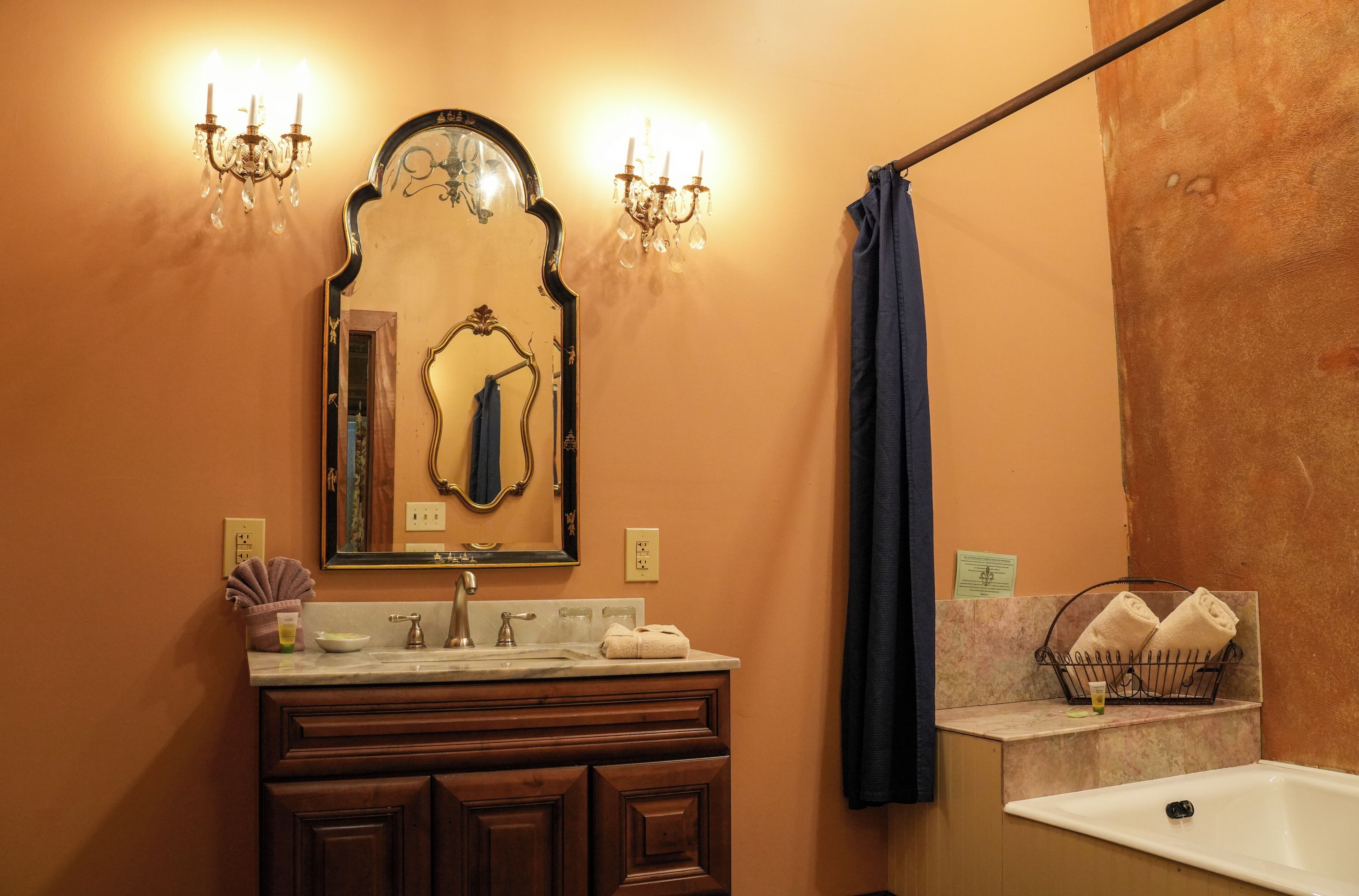 A bathroom with a vanity, a mirror, a chandelier, a towel rack, and a bathtub.