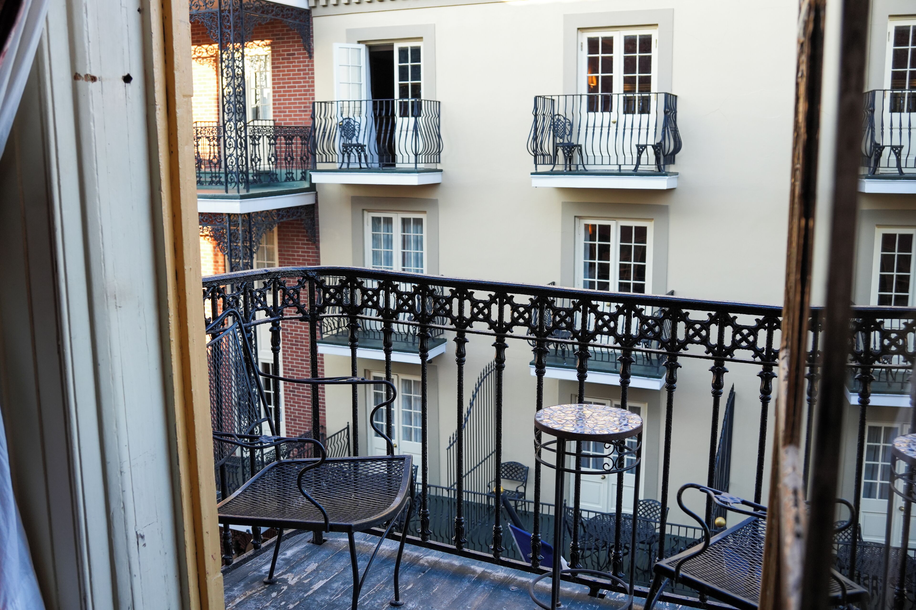 A balcony with metal railings, two chairs, and a small round table.