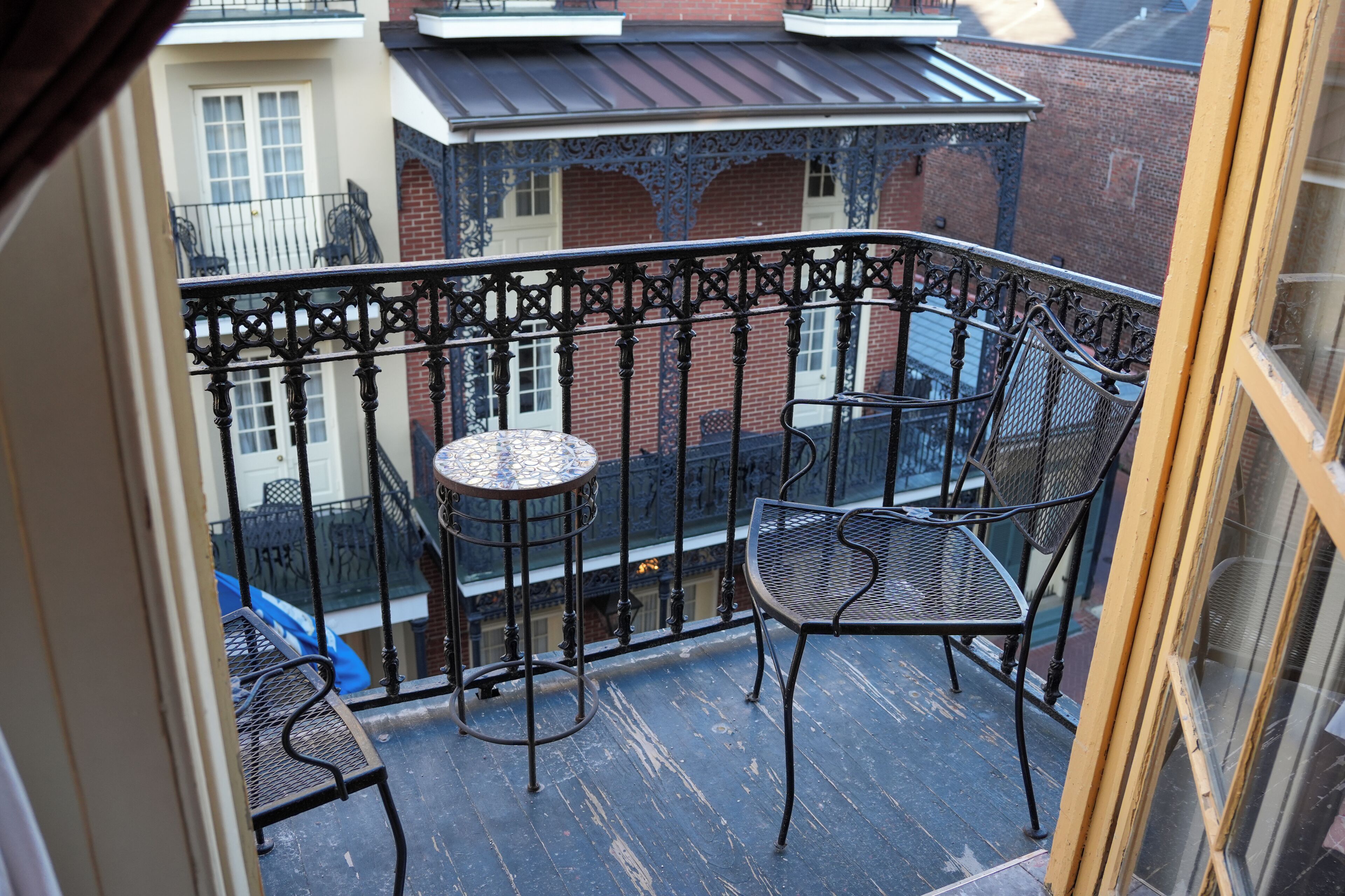 A balcony with a wrought iron railing, a small round table, and two chairs.