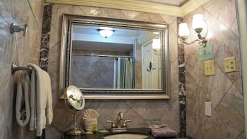 A bathroom with a large mirror, a sink, a towel rack, and a wall-mounted light fixture.