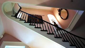 Una escalera con diseño curvo, barandilla y un espejo en la pared.