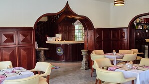 Un restaurante con paneles de madera, mesas y sillas blancas.