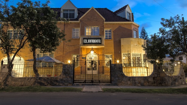 Un hotel con fachada de ladrillo, entrada protegida por una reja y un letrero que dice "ECO_BOUTIQUEHOTEL".