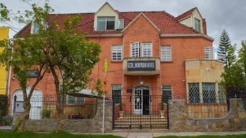 Un edificio de ladrillo de dos pisos con techo de tejas rojas, un cartel que dice