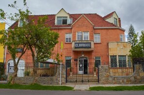 Een gebouw van baksteen met twee verdiepingen, een dak van rode tegels, een bordje met de tekst 'ECO_BOUTIQUEHOTEL' en een hekwerkentree.