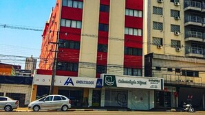A multi-story building with a red and white facade, featuring a sign for 'Ambassador Hotel' and 'Odontologia'.
