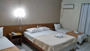 A hotel room with two beds, a bedside table with a phone, a wall-mounted air conditioner, and a curtain.