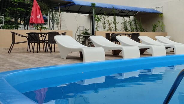 A swimming pool with lounge chairs and a slide. - Hotel Lawrence (Foz do Iguaçu)