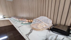 A buffet setup with bread and pastries in clear containers, a laptop on the counter, and a telephone. - Hotel Lawrence (Foz do Iguaçu)