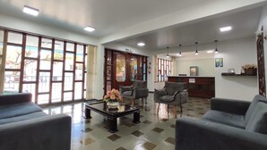A reception area with a check-in counter, seating, and large windows. - Hotel Lawrence (Foz do Iguaçu)
