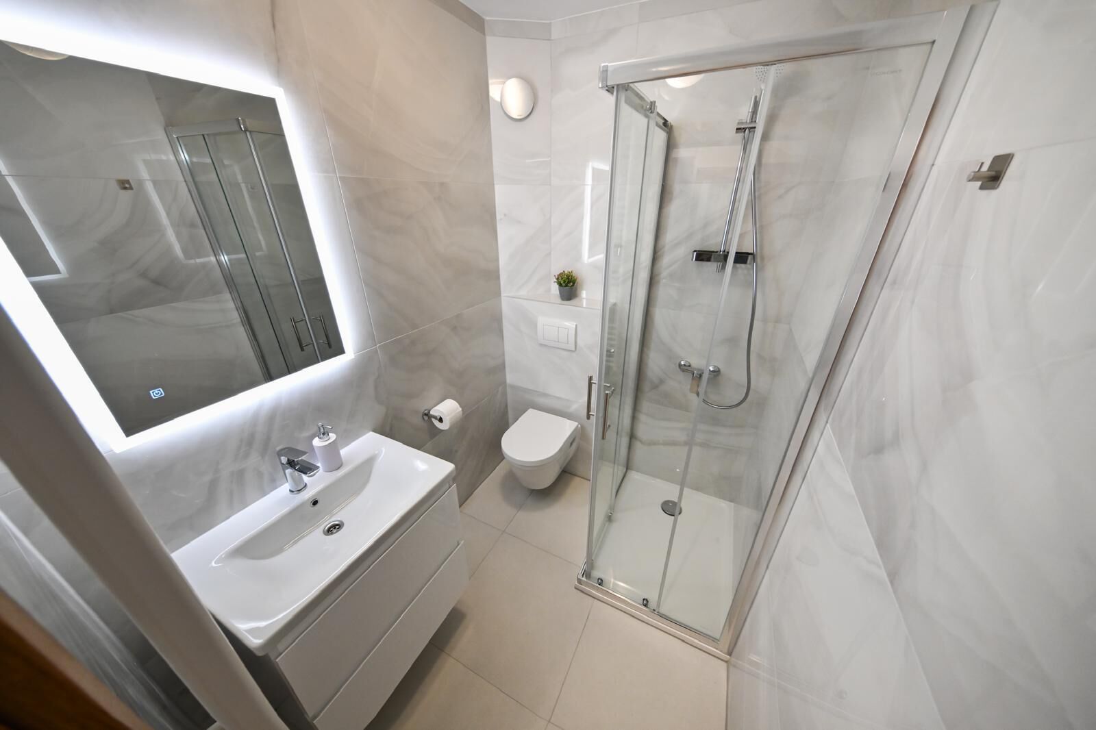 Une salle de bain moderne avec une douche à parois de verre, un lavabo blanc et des toilettes.