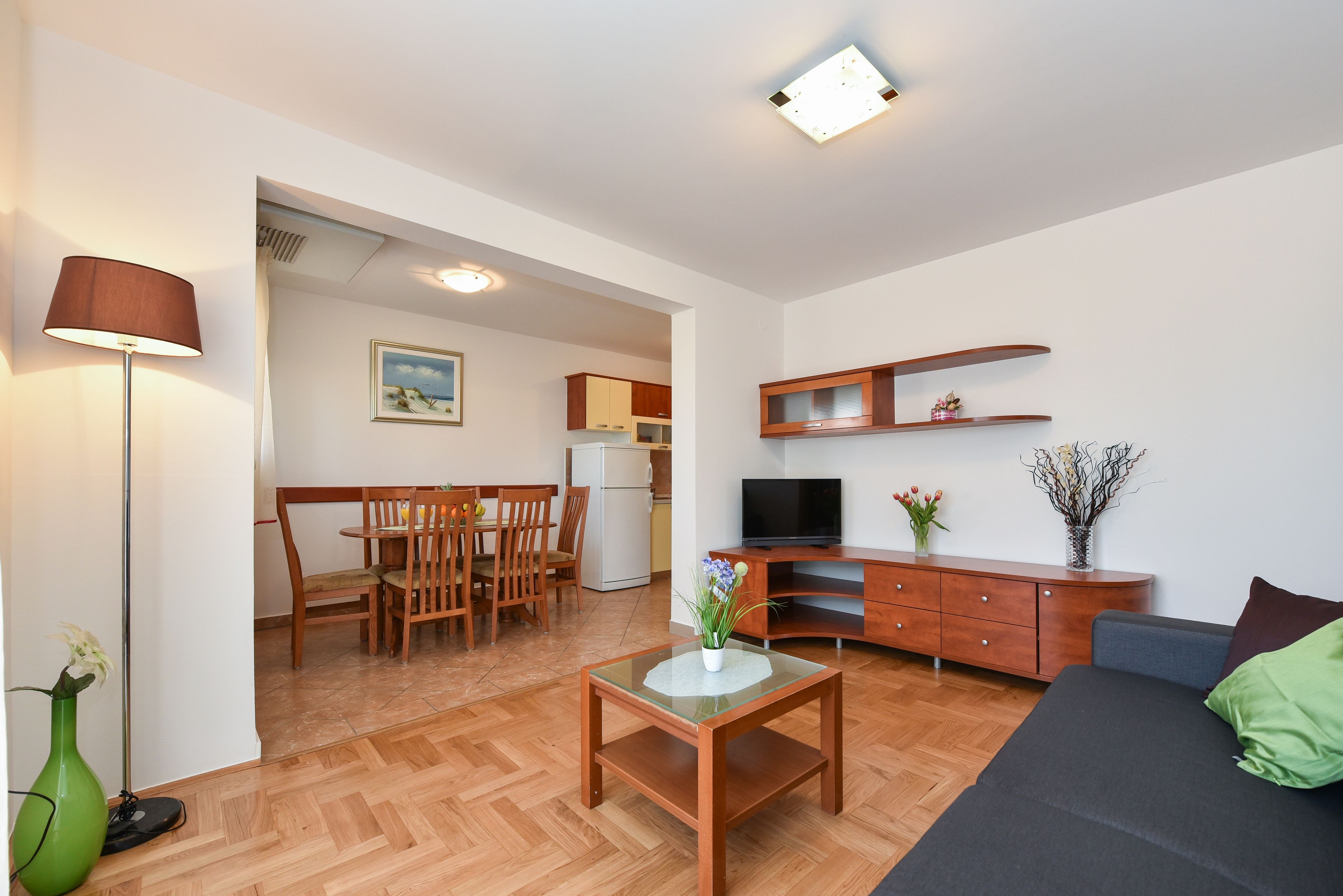 Una sala de estar moderna con un sofá, una mesa de centro, un televisor y un comedor con sillas y una mesa.