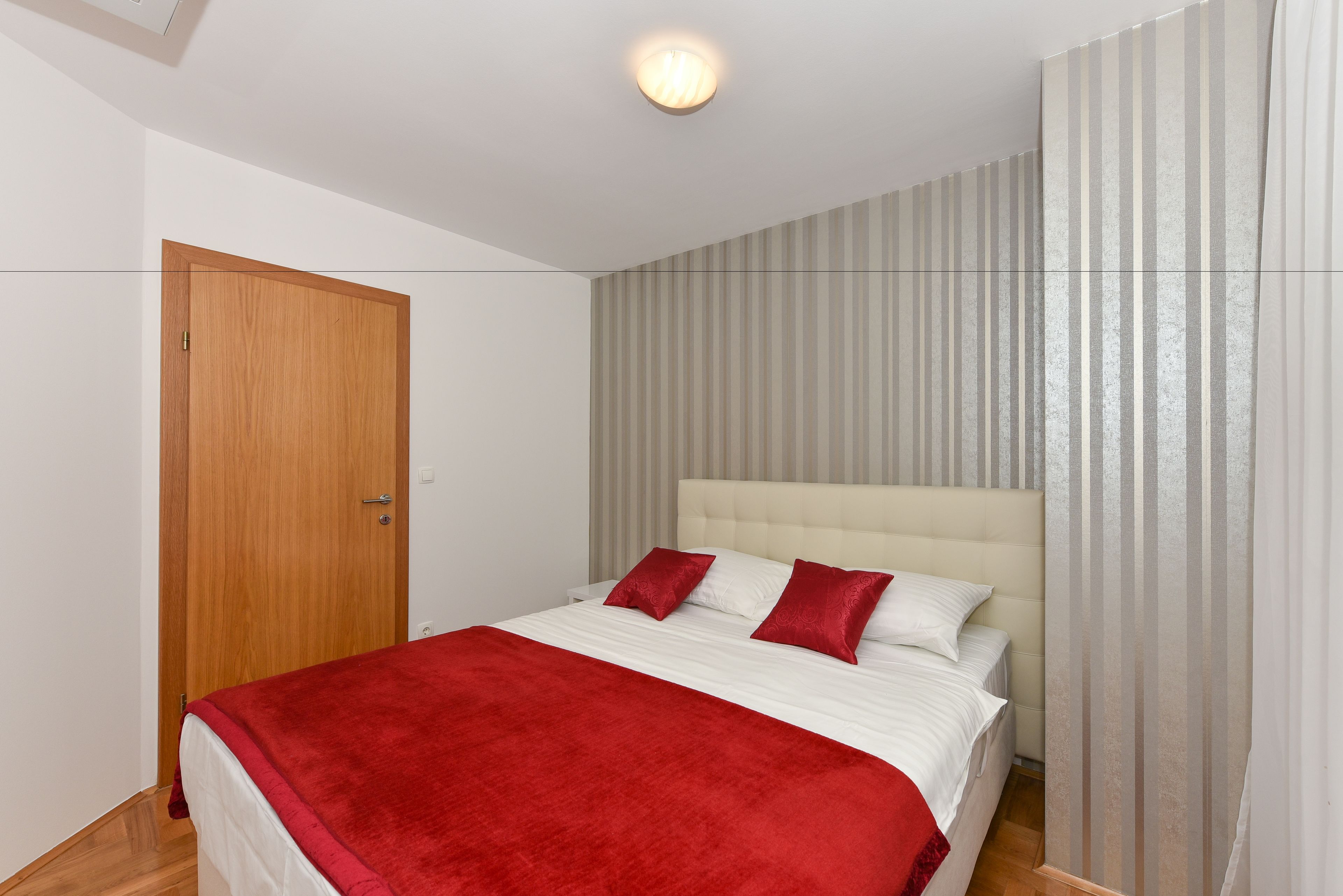 A bedroom with a bed, a wooden door, and a striped wall.