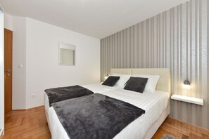 Quarto com cama grande, duas mesas de cabeceira, espelho e parede listrada.