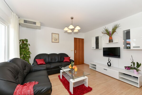 A modern living room with a black leather sofa, a glass coffee table, and a red rug. - Villa Gravić (Zadar)