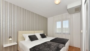 A double bed with white and black bedding, a bedside table, and a wall-mounted light fixture. - Villa Gravić (Zadar)