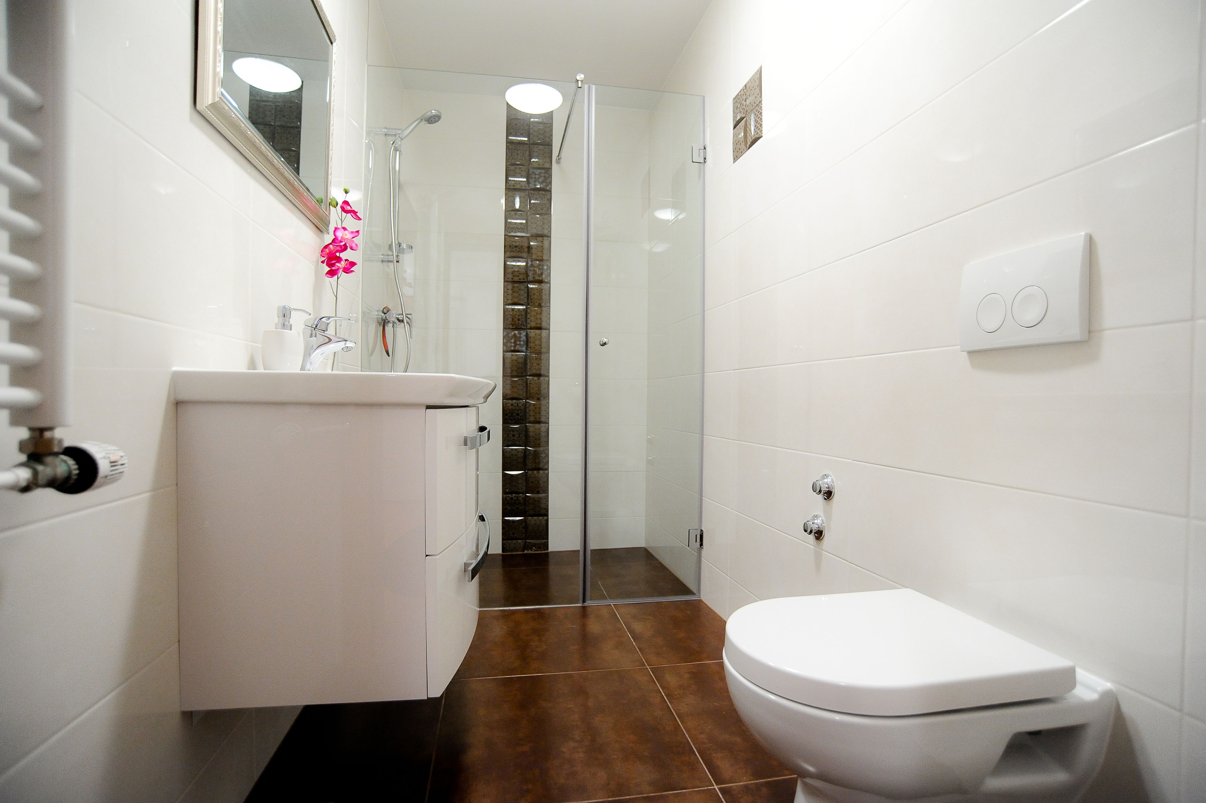 Ein modernes Badezimmer mit Waschbecken, Toilette und Dusche in Weiß.