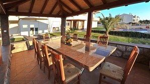An outdoor patio with a marble table and wooden chairs, a small pool, and a view of the surrounding area. - Villa Gravić (Zadar)