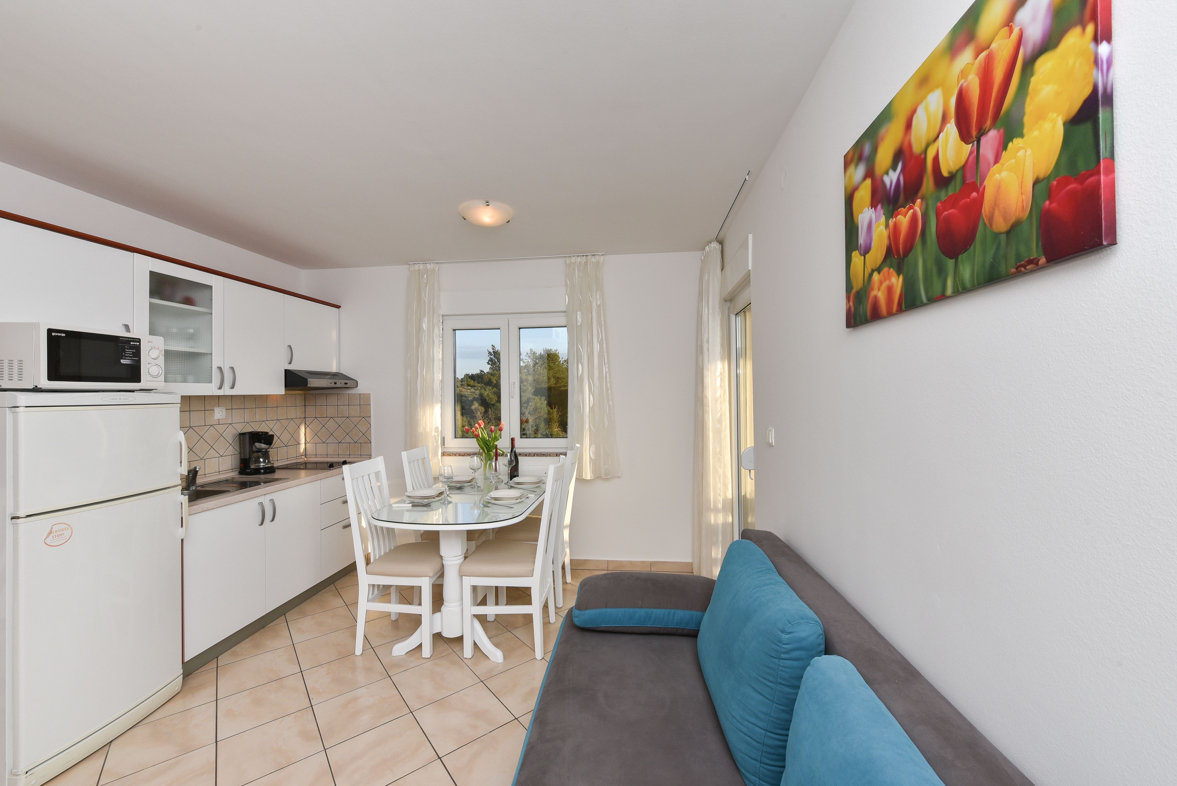 A compact kitchen with white cabinets, a microwave, and a dining area with a table and chairs.