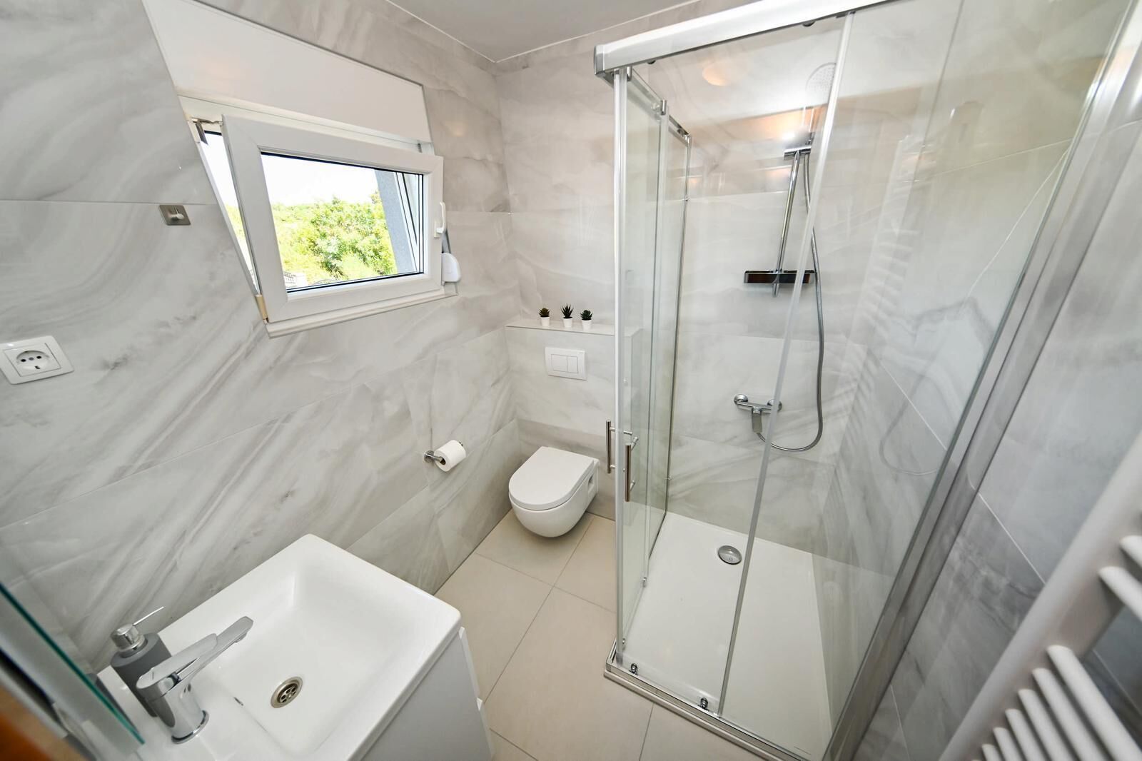 A modern bathroom with a glass-enclosed shower, a toilet, and a sink.