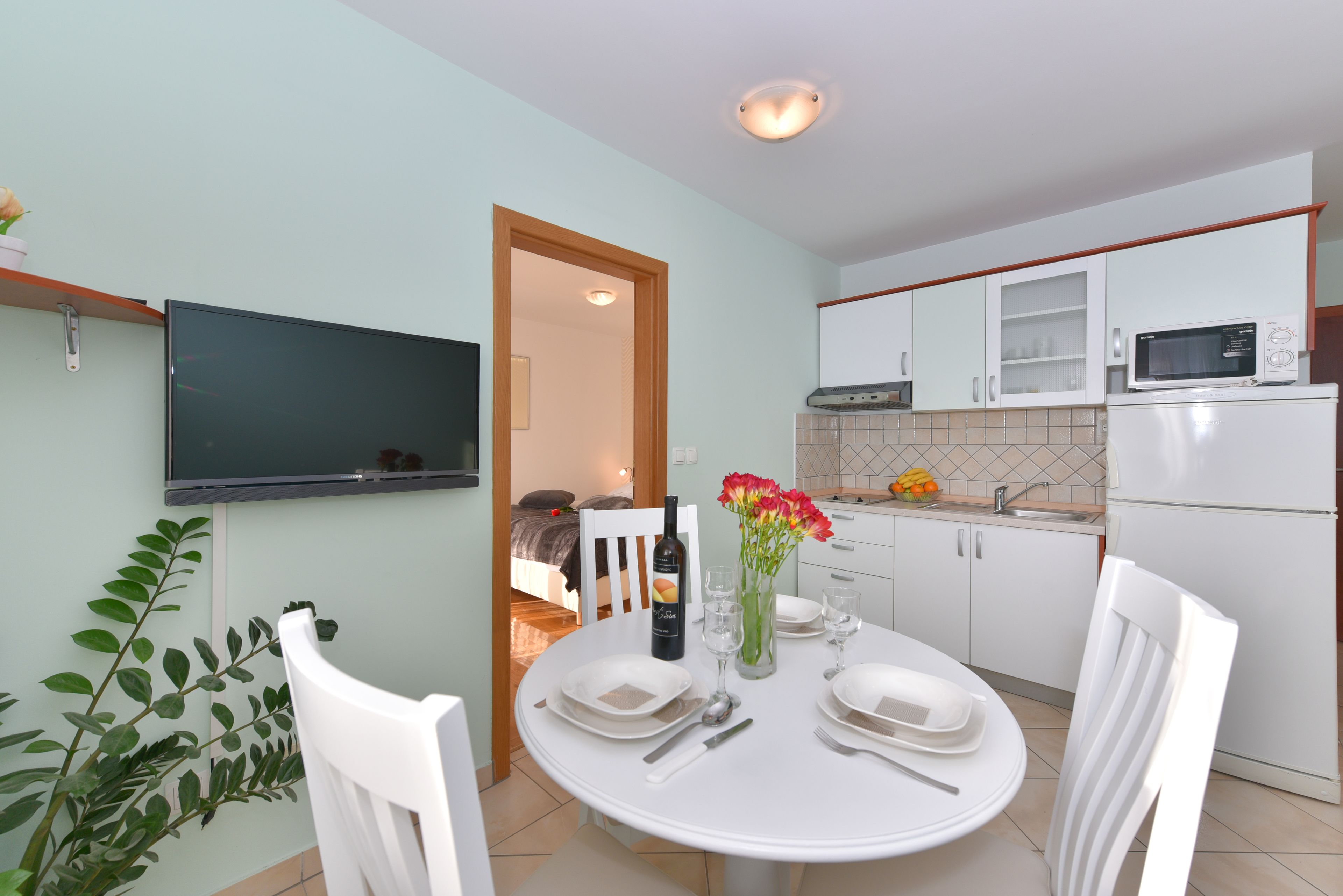 A modern kitchen with white cabinets, a microwave, and a dining table set for two.