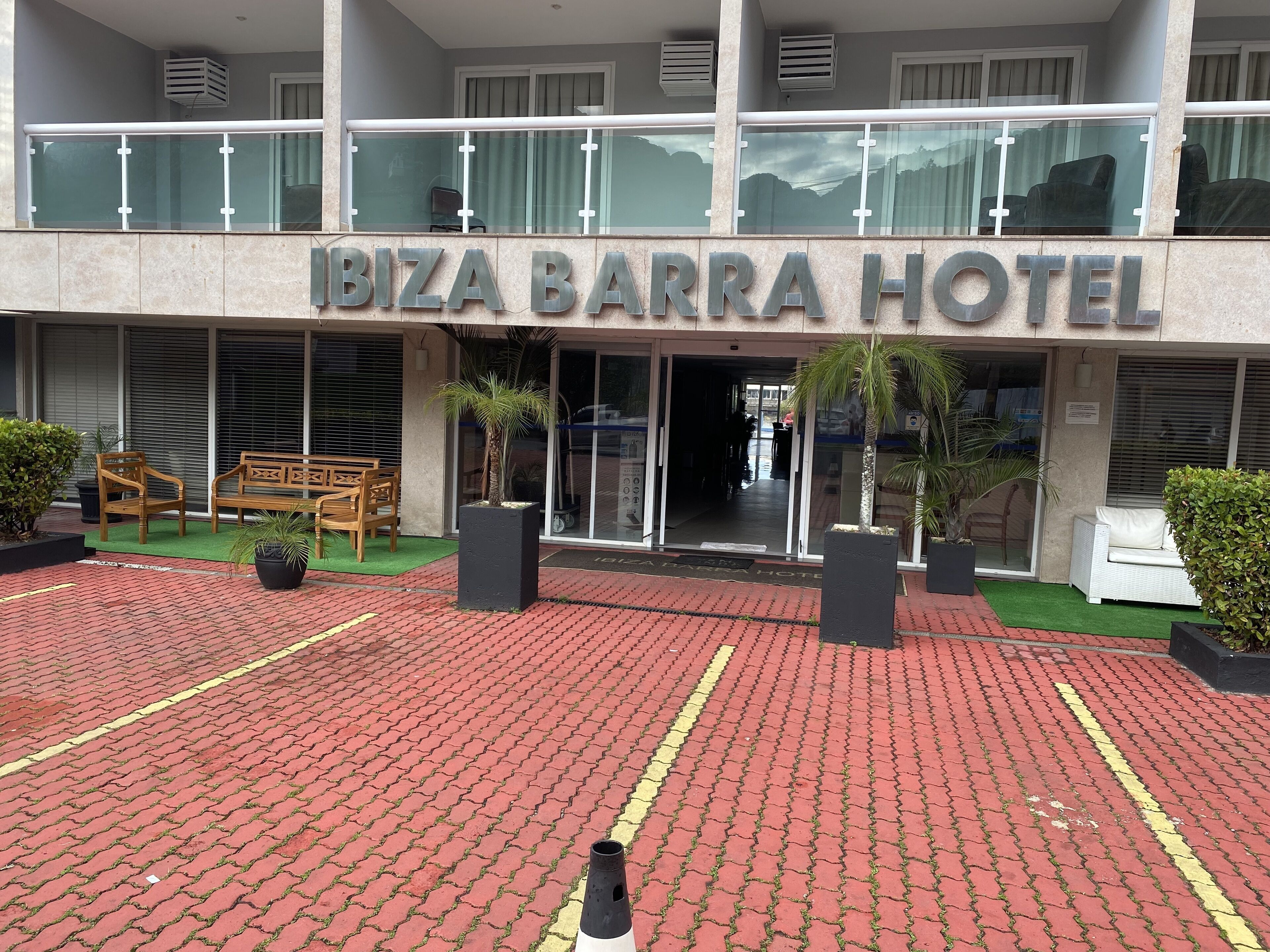 Esterno dell'Ibiza Barra Hotel, con ingresso pavimentato, area salotto esterna e piante in vaso.