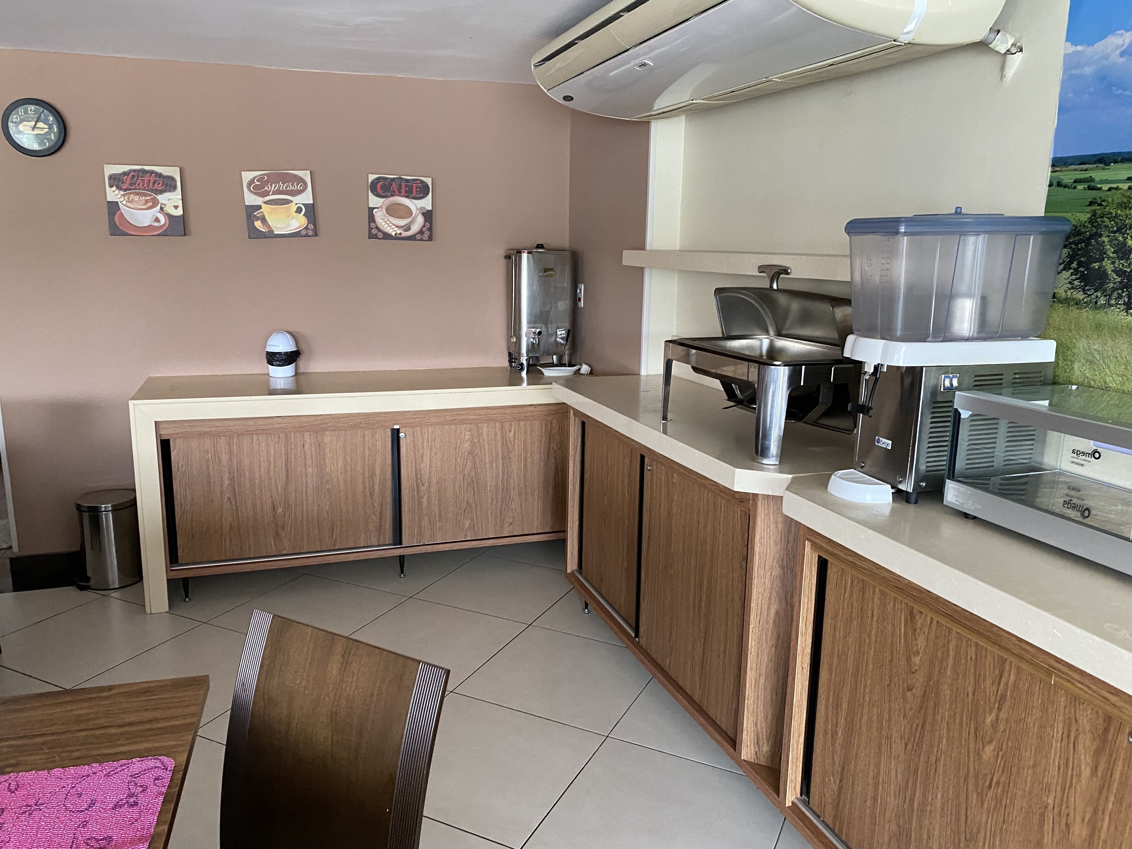 A kitchenette with a coffee machine, a trash bin, and wall decorations.