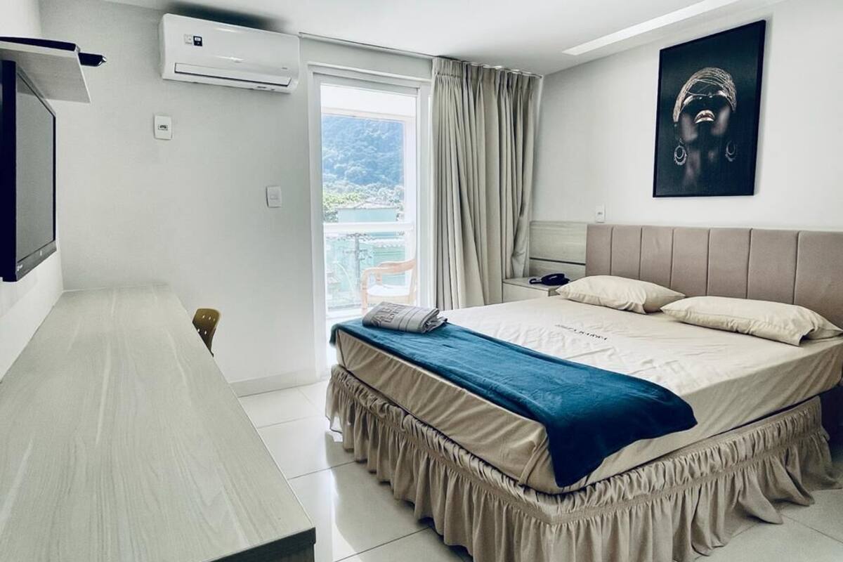 A modern bedroom with a bed, a desk, and an air conditioning unit.