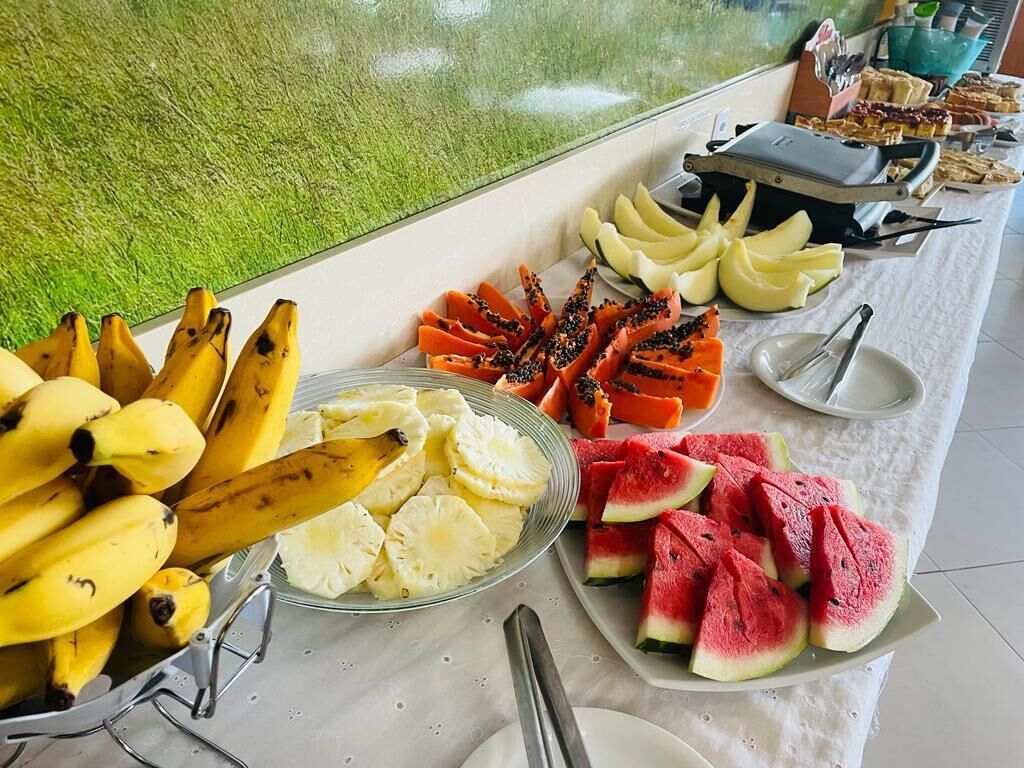 Une table de buffet proposant une variété de fruits, notamment des bananes, des ananas, des papayes et des pastèques.