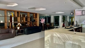 A modern living room with a wooden bookshelf, a sofa, a coffee table, and a desk with a computer. - Ibiza Barra Hotel (Rio de Janeiro)