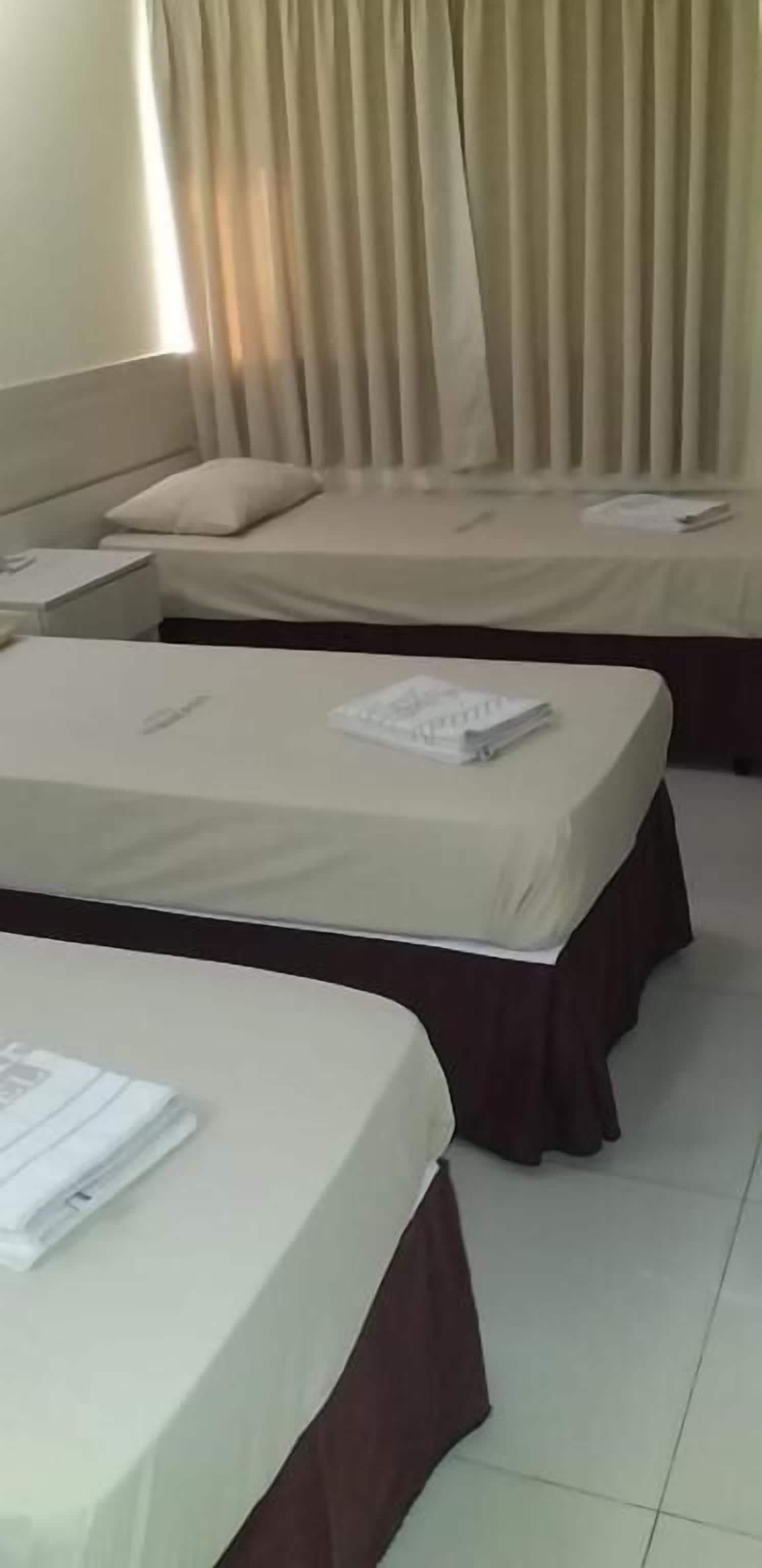 Habitación de hotel con dos camas, cada una con cubrecolchón oscuro y una almohada.