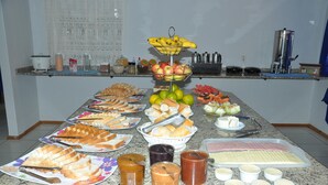 A buffet table with various food items including bread, fruits, and condiments. - Hotel Blue Star II (Foz do Iguacu)