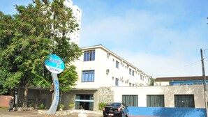 A hotel sign with a contact number, a building with multiple windows, and a parked car. - Hotel Blue Star II (Foz do Iguacu)