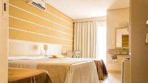 Una camera d'albergo con due letti, un bagno con lavandino e specchio, e un angolo cottura.
