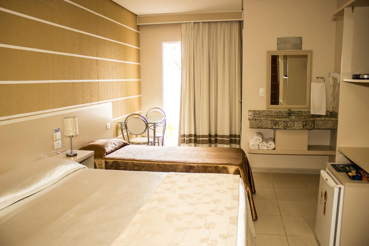 A hotel room with two beds, a bathroom with a mirror, a sink, and a refrigerator.