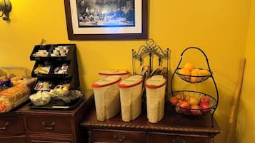 A kitchen counter with jars of grains, a basket of apples, and a tray of bread.