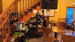 A cozy interior with a staircase, a wooden table, chairs, and shelves stocked with various items. - Glacier Guides Lodge (West Glacier)