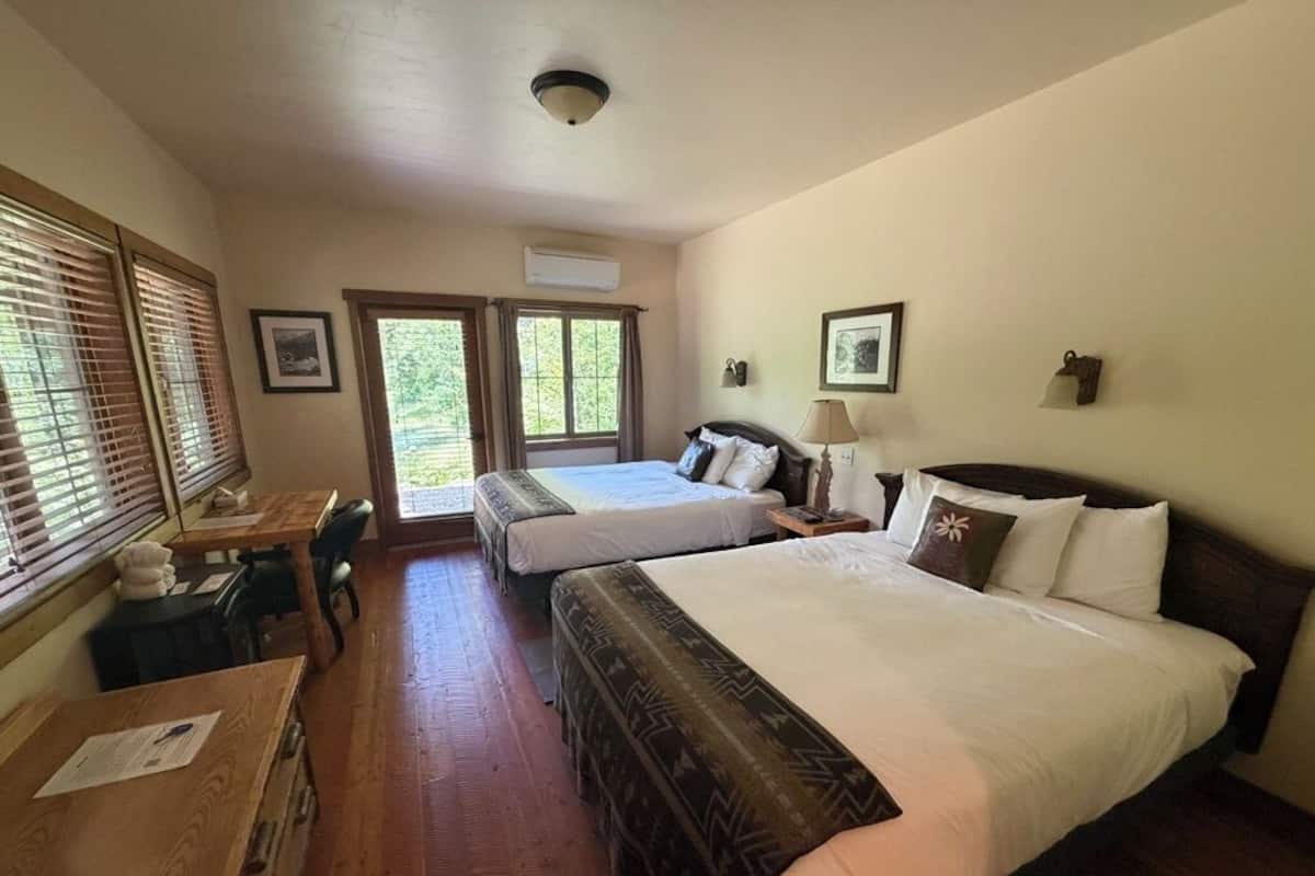 Habitación de hotel con dos camas, un escritorio y una ventana con persianas.