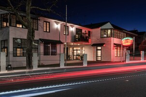 A motel with a neon sign, a balcony, and a well-lit facade.