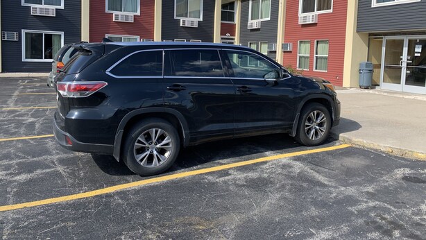 Ein schwarzer SUV steht in einer Parkhausgarage mit moderner Gebäudefassade.