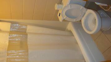 Une salle de bain avec des toilettes, un rideau de douche blanc et une baignoire blanche.