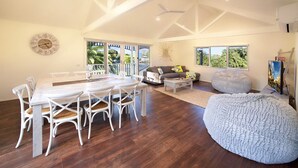 A spacious living area with a dining table, white chairs, a gray sofa, and a large bean bag. - Boathouse Resort Studios & Suites (Blairgowrie)