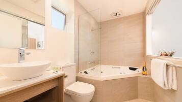 A modern bathroom with a large white sink, a glass-enclosed shower, a bathtub, and a toilet.