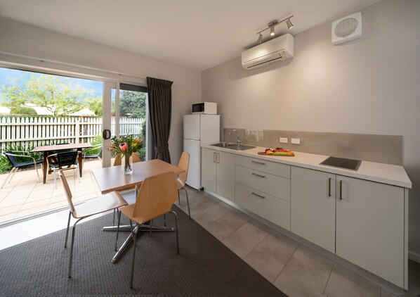 A modern kitchen with a dining area, featuring a built-in oven, a sink, and a countertop with a tablet.